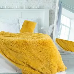 Żółty koc włochaty na łóżku w sypialni