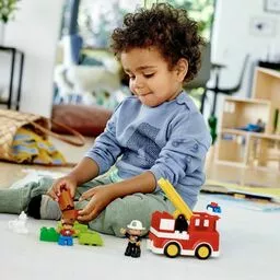 Chłopiec bawi się w domu zestawem Lego Duplo straż pożarna Chłopiec bawi się w domu zestawem Lego Duplo straż pożarna
