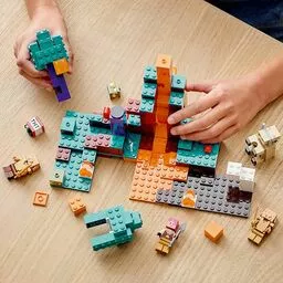Zestaw predstawiający klocki Lego Minecraft lezące na stole w pokoju