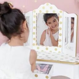uśmiechnięta dziewczynka udająca robienie makijażu przy toaletce